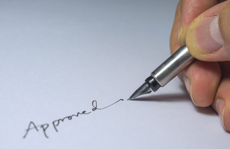 closeup-approved-signature-with-fingers-pen-light-bulb-from-left-side