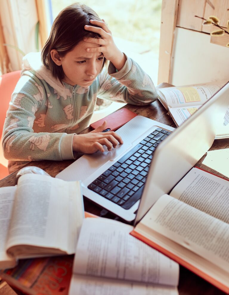 Schoolgirl does homework on the laptop at the home and looks con